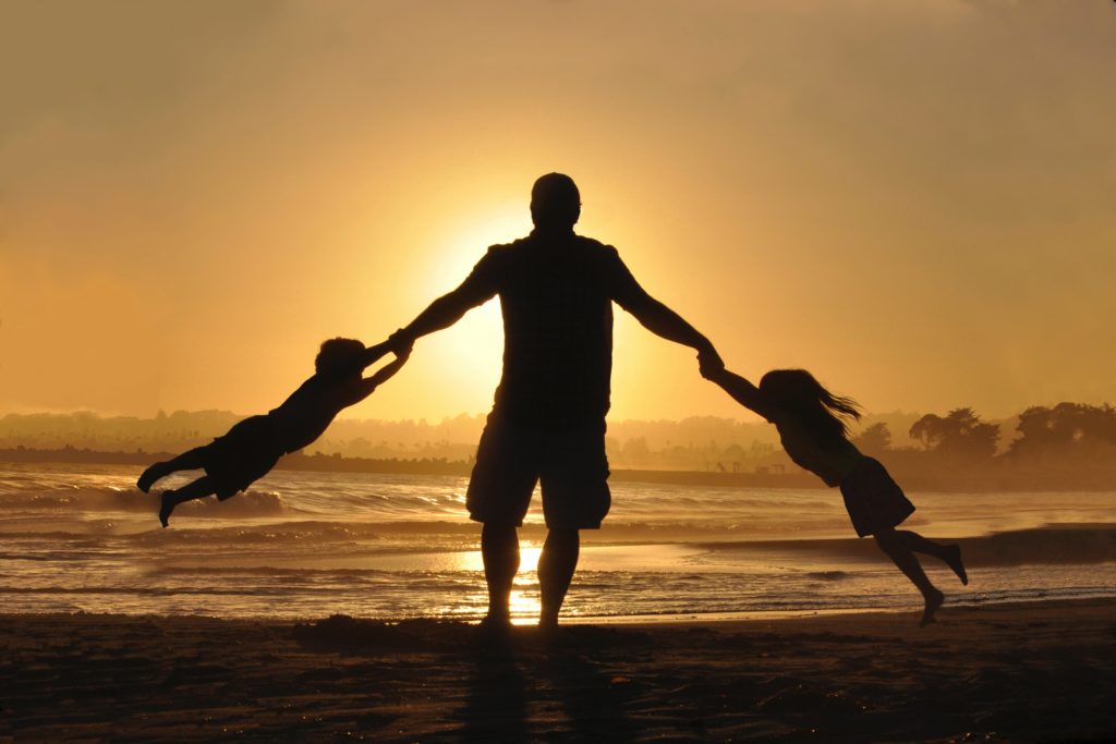 Tata bawiący się na plaży z dziećmi