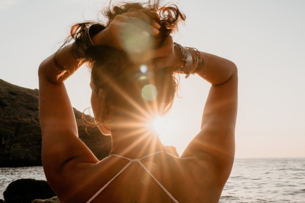 Zdjęcie dziewczyny odwróconej tyłem w morzu o zachodzie słońca