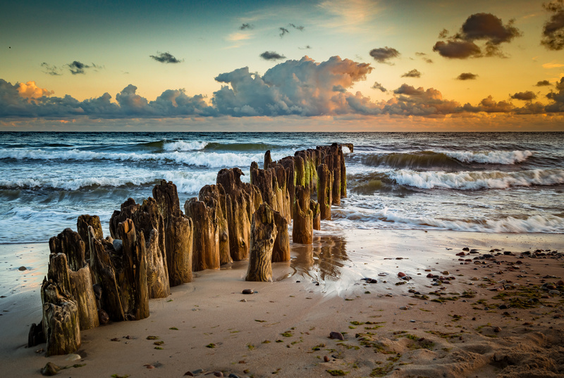 Falochron na bałtyckiej plaży o zachodzie słońca