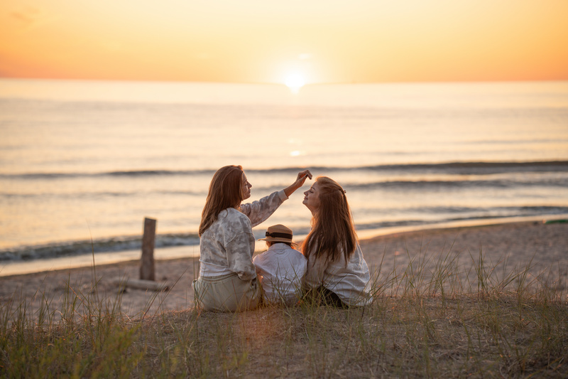 Mama z dziećmi na plaży o zachodzie słońca