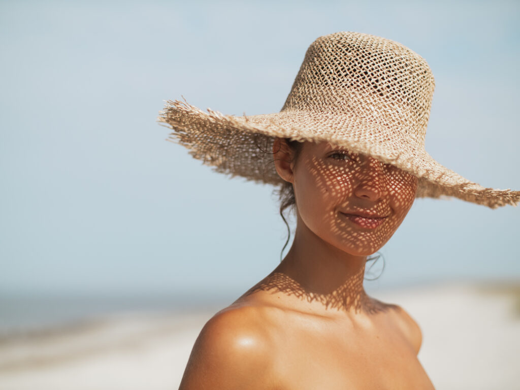 Kobieta na plaży nudystów w słomianym kapeluszu