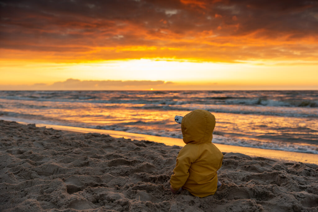 Dziecko oglądające zachód słońca nad morzem w Kołobrzegu