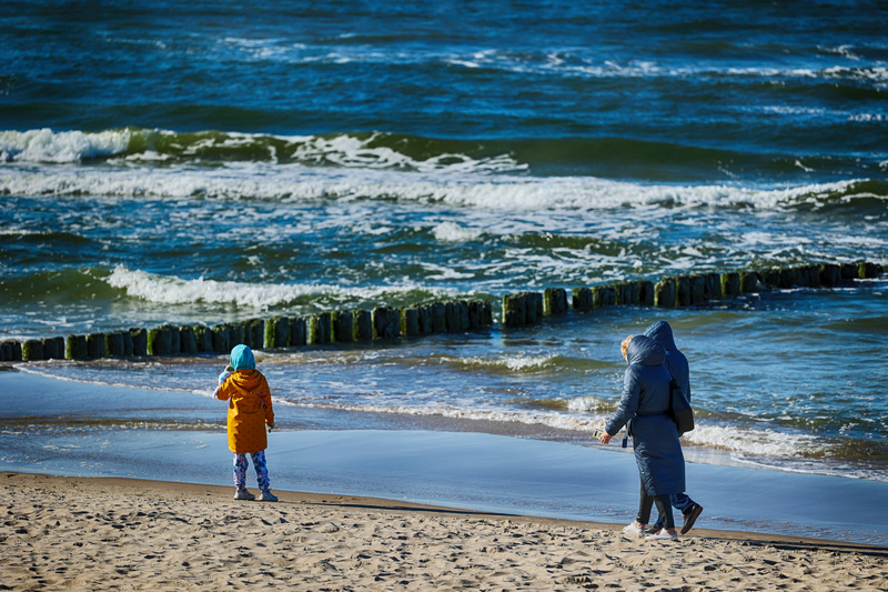 Dziecko z dwoma osobami na plaży zimą