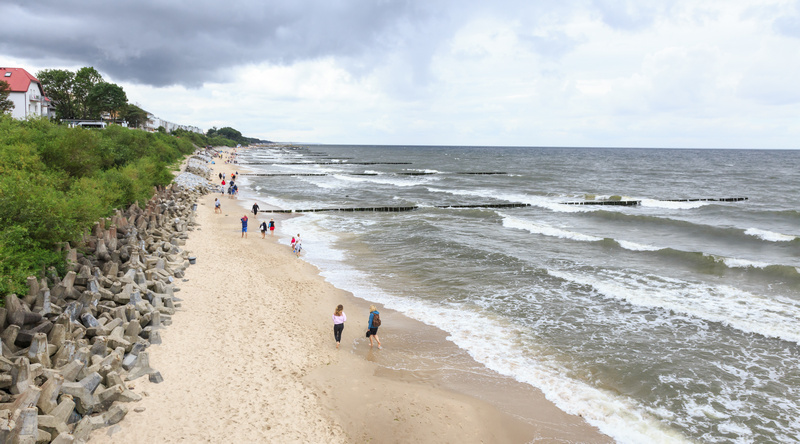 Ludzie spacerujący po plaży w Ustroniu Morskim w pochmurny dzień
