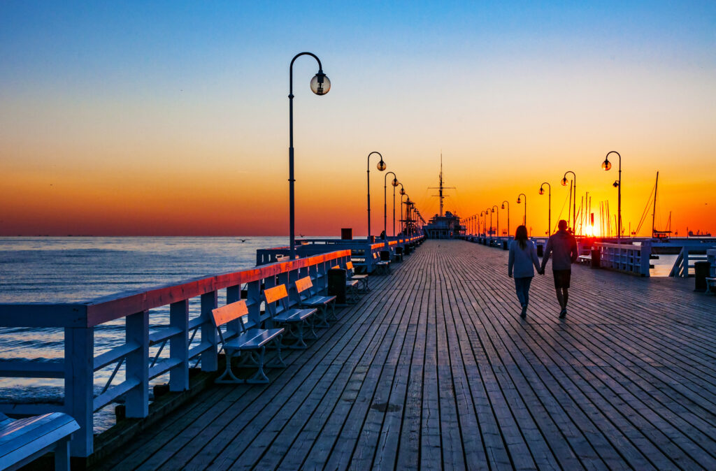 Para spacerująca po molo w Sopocie o wschodzie słońca
