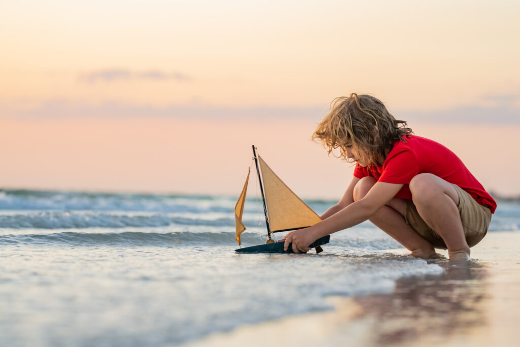 Chłopiec bawiący się statkiem na plaży w Polsce podczas wakacji