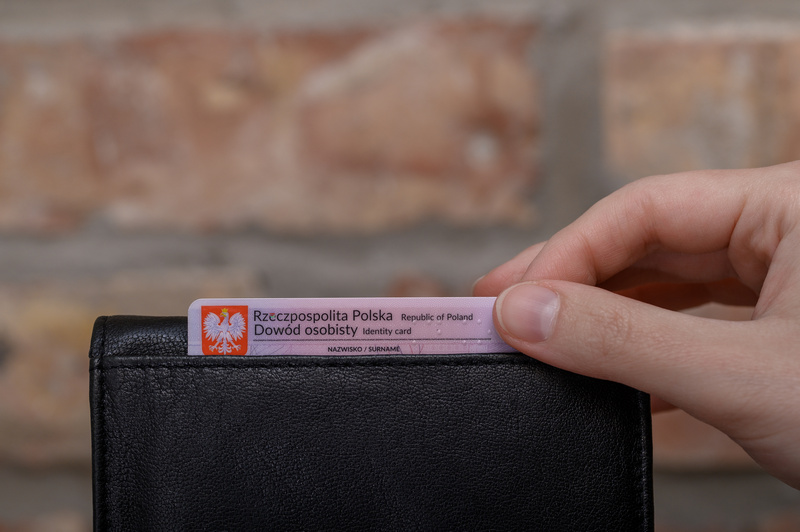 Dłoń wkładająca do portfela dowód osobisty