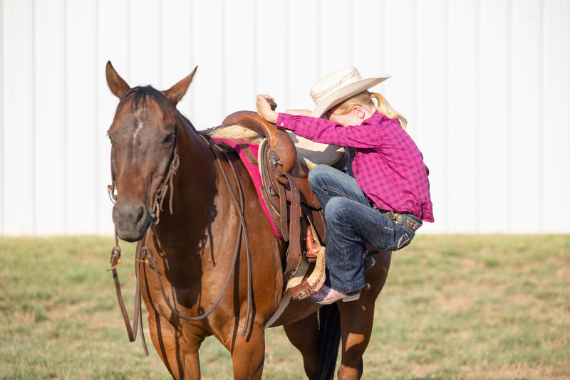 Dziewczyna w kowbojskim stroju wsiadająca na konie