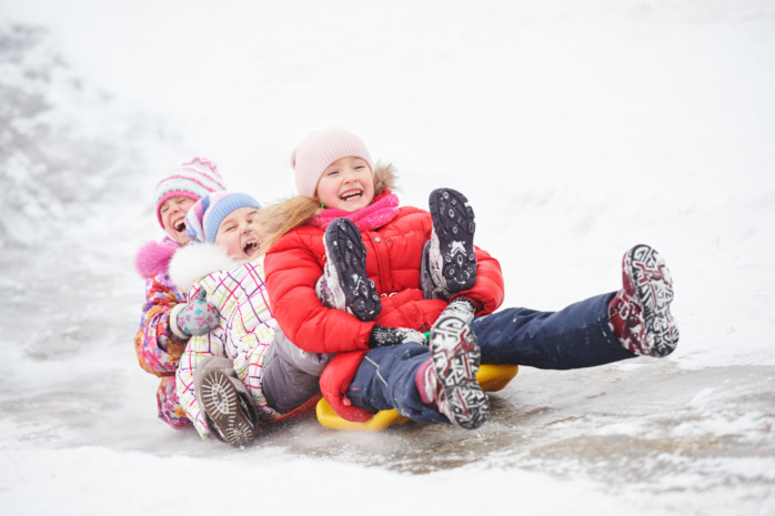 Dzieci zjeżdżające na lodzie podczas ferii zimowych