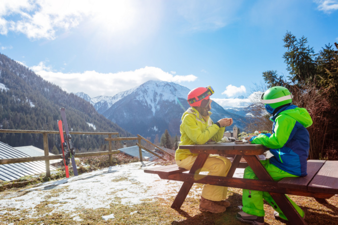 Matka z synem na wyjeździe narciarskim odpoczywają przy posiłku z widokiem na góry