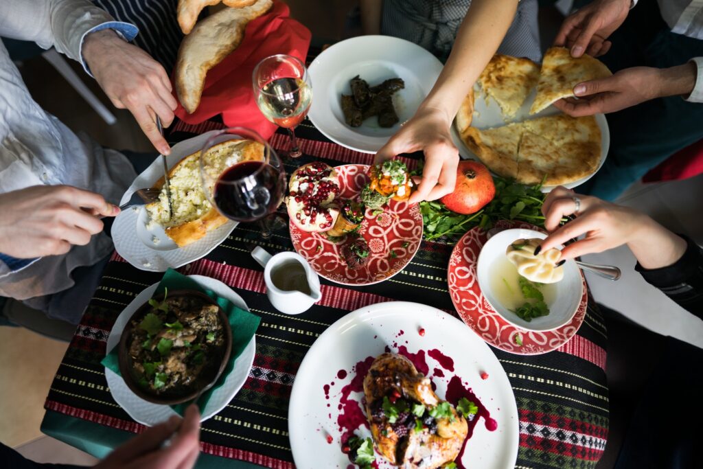 Grupa osób ciesząca się wspólnym posiłkiem w gruzińskiej restauracji Granat w Warszawie