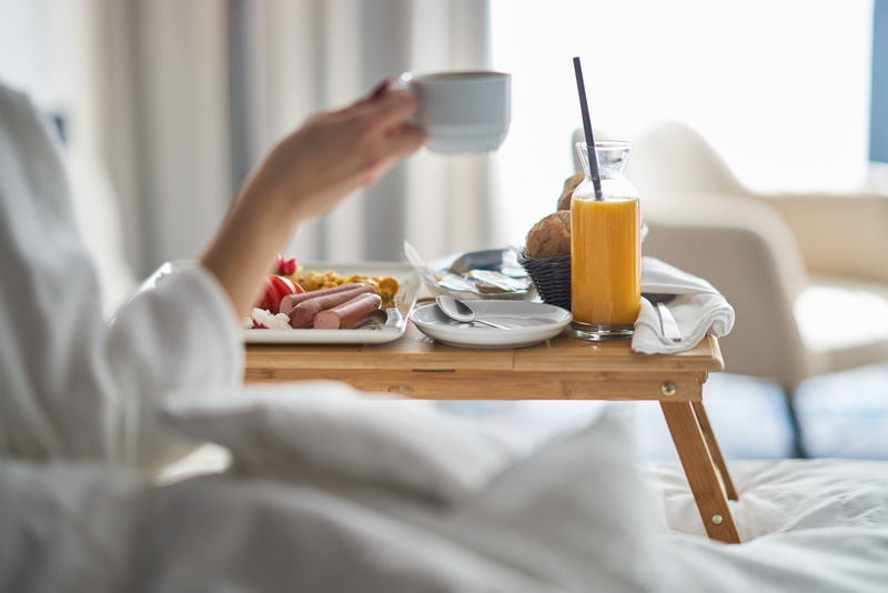 Kobieta jedząca śniadanie na łóżku w pokoju hotelowym