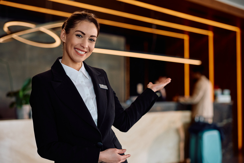 Kobieta z obsługi hotelu wykonująca zapraszający gest ręką
