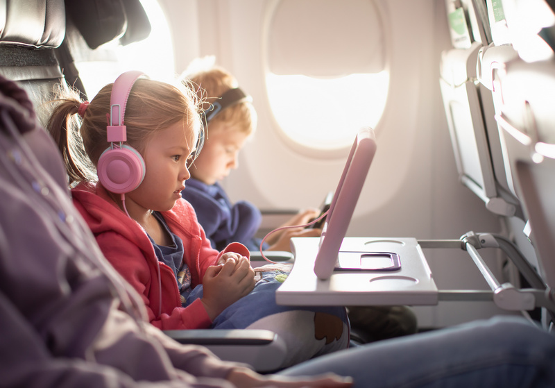 Dzieci w samolocie zajęte oglądaniem filmów