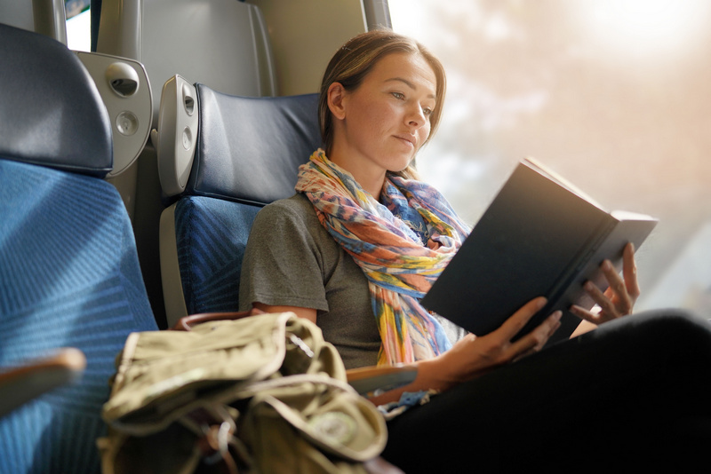 Kobieta czytająca książkę w trakcie jazdy pociągiem
