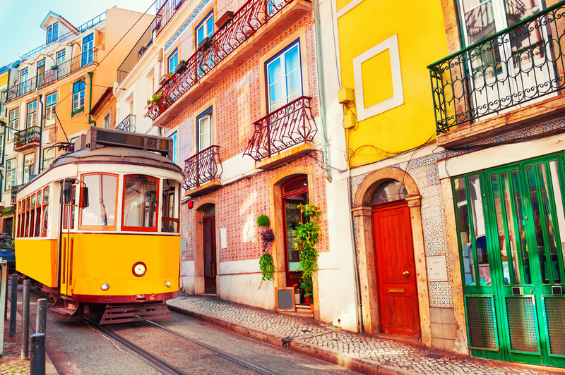 Żółty tramwaj na uliczce pięknej i kolorowej Lizbony
