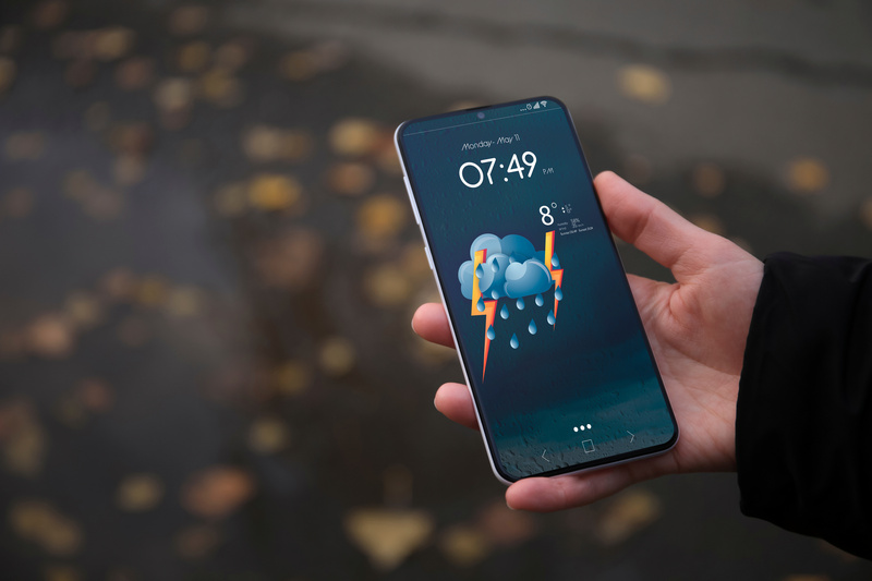 Mężczyzna z telefonem z prognozą pogody jesienią