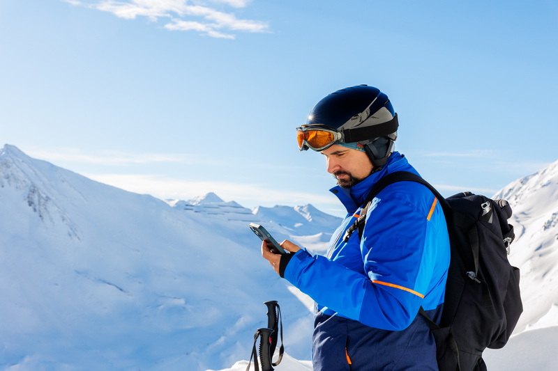 Mężczyzna zimą w górach z telefonem w ręce