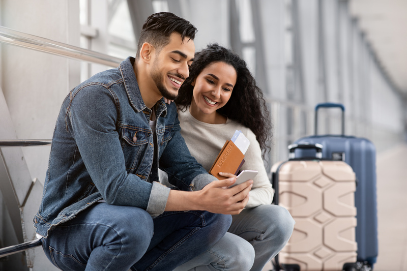 Para z walizkami na lotnisku patrząca w telefon