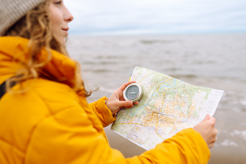 Podróżniczka z mapą i kompasem stojąca na plaży