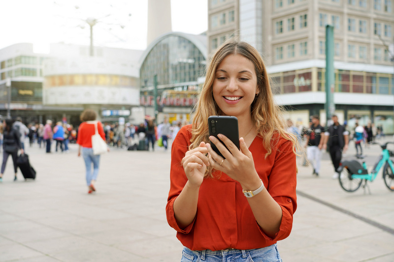 Uśmiechnięta kobieta w Berlinie sprawdzająca coś na telefonie