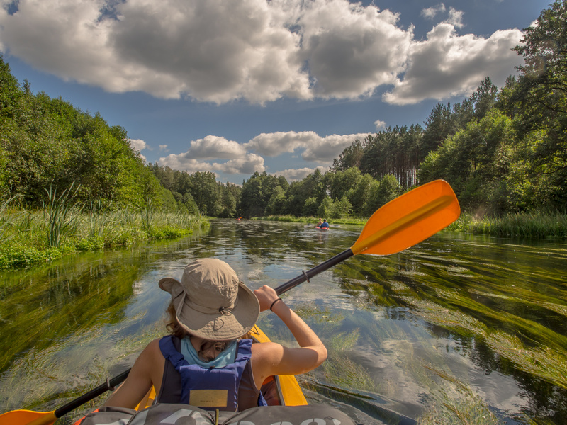 Osoba w kapeluszu wiosłująca w kajaku