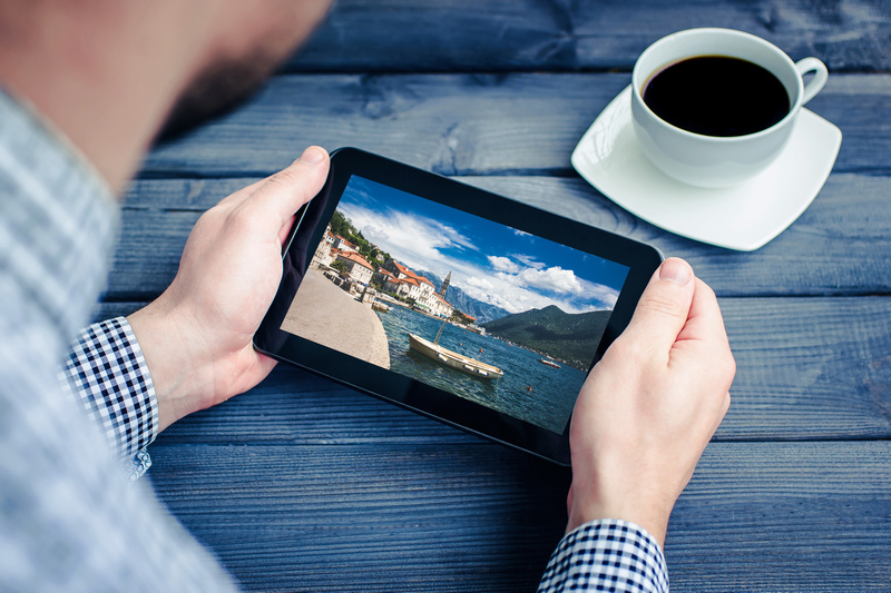 Mężczyzna trzymający tablet ze zdjęciem wakacyjnej destynacji