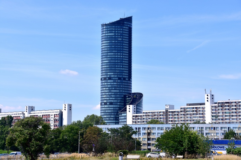 Wrocławski Sky Tower górujący nad sąsiadującymi blokami
