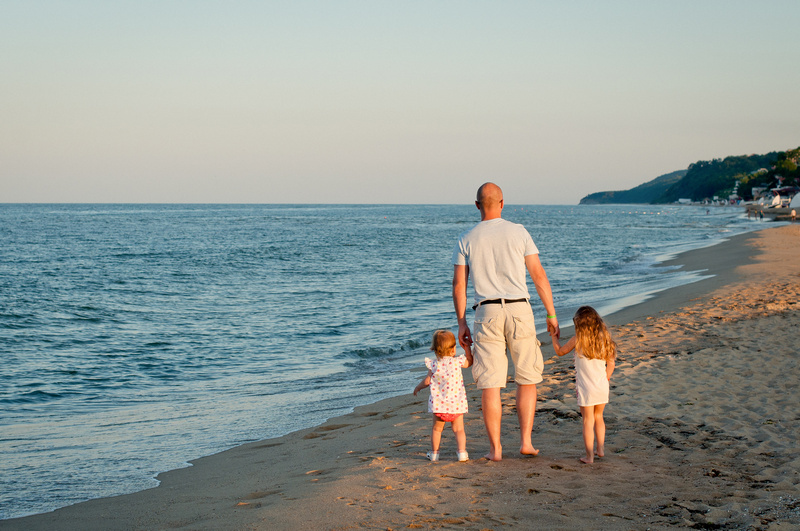 Ojciec z dziećmi spaceruje po plaży
