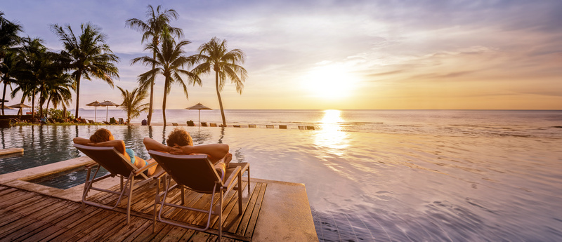 Para leżąca na leżakach na pomoście w tropikach o zachodzie słońca