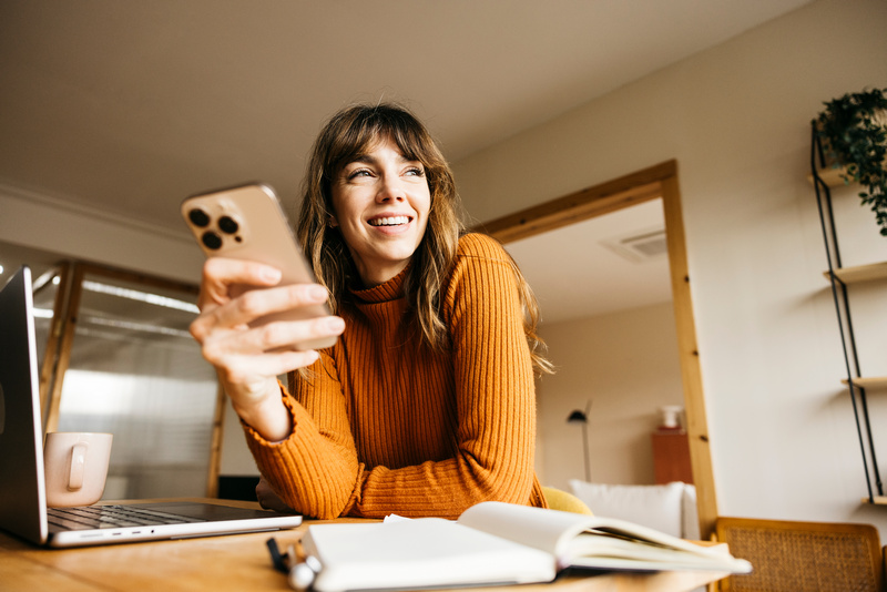 Uśmiechnięta kobieta trzymająca w dłoni smartfon