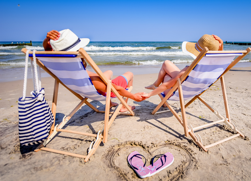 Dzieci w kapeluszach siedzące na leżakach nad morzem