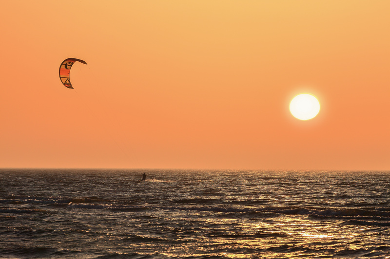 Uprawianie kitesurfingu w Łebie o zachodzie słońca
