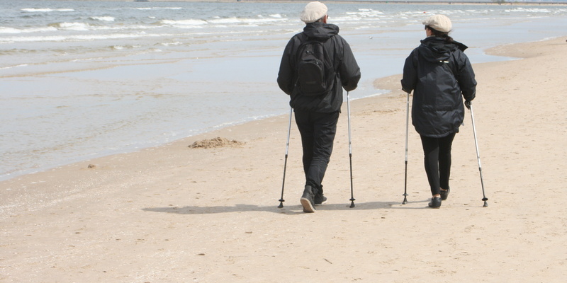 Para starszych osób podczas nordic walking na plaży
