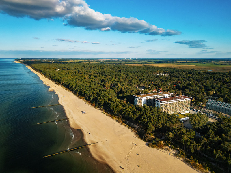 Długa, piaszczysta plaża nad Bałtykiem z widocznym resortem wypoczynkowym