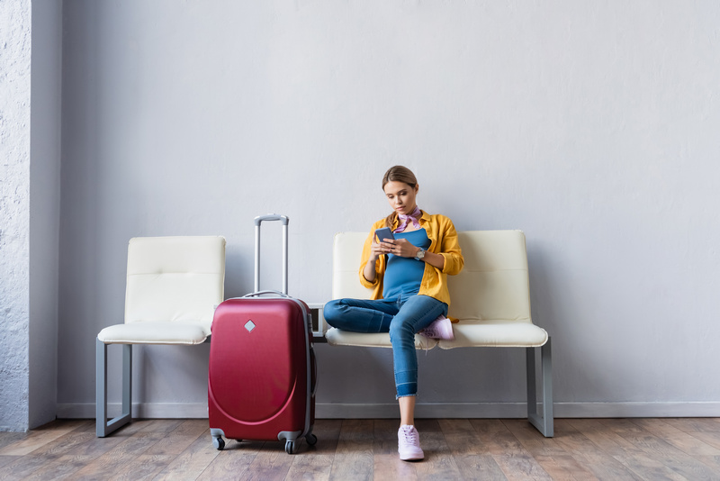 Siedząca na krześle kobieta w ciąży z walizką