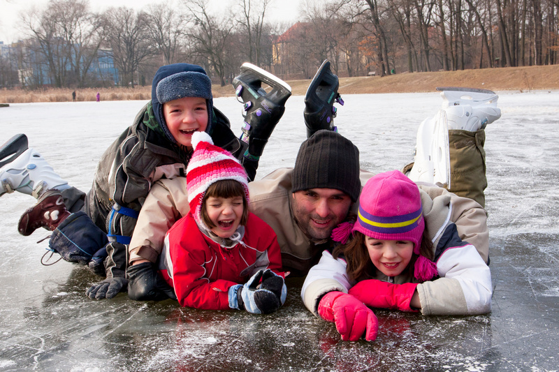 Dzieci z tatą na łyżwach leżące na lodzie