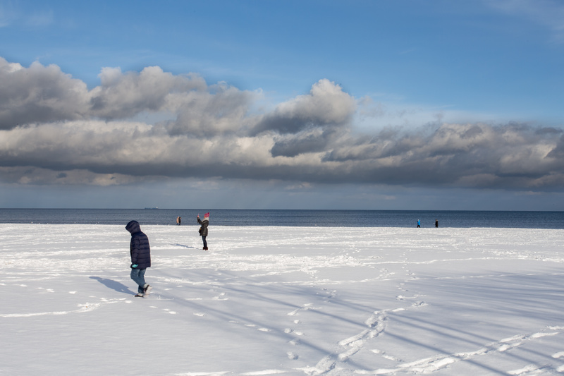 Ludzie spacerujący po ośnieżonej plaży nad morzem