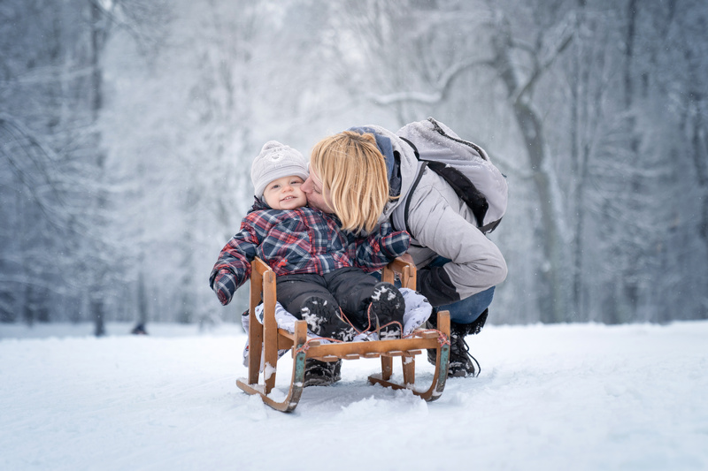 Mama całująca dziecko na sankach w parku