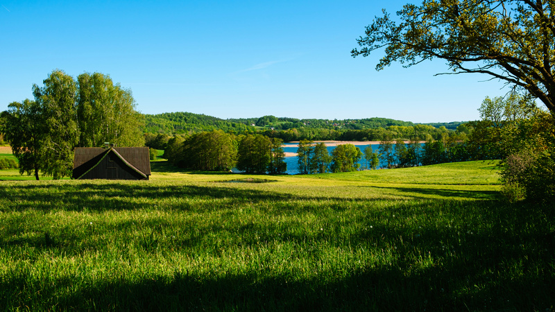Dach drewnianego domku w polu z jeziorem w tle w Kaszubskiej Szwajcarii