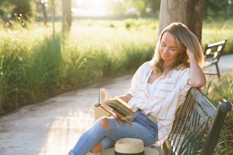 Kobieta siedząca na ławce w parku i czytająca książkę