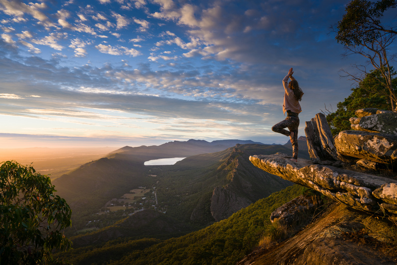 Kobieta w figurze z jogi w górach oglądająca zachód słońca