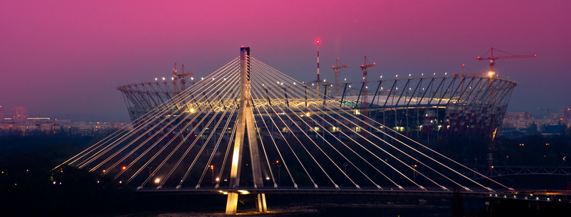 Most Świętokrzyski i Stadion Narodowy nocą z różową łuną na niebie
