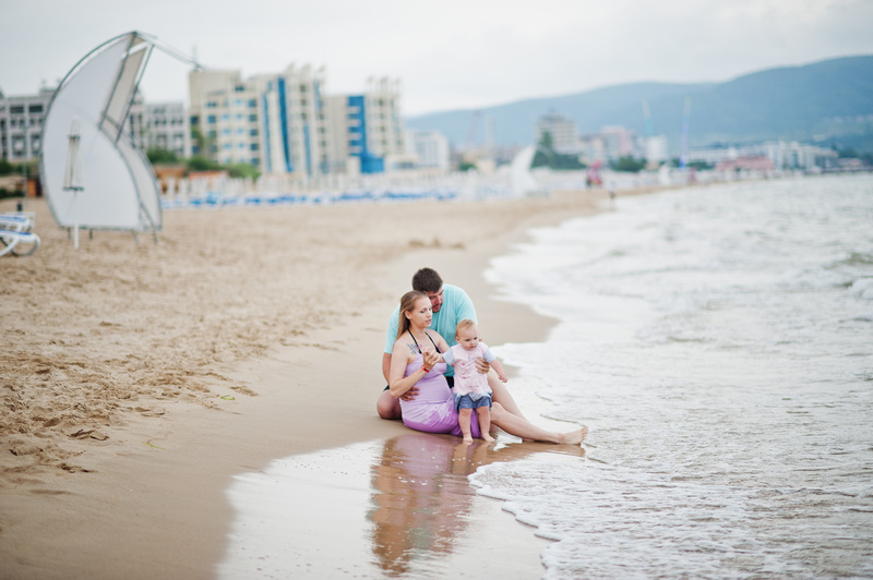 Rodzice z małym dzieckiem siedzący na brzegu morza w Słonecznym Brzegu