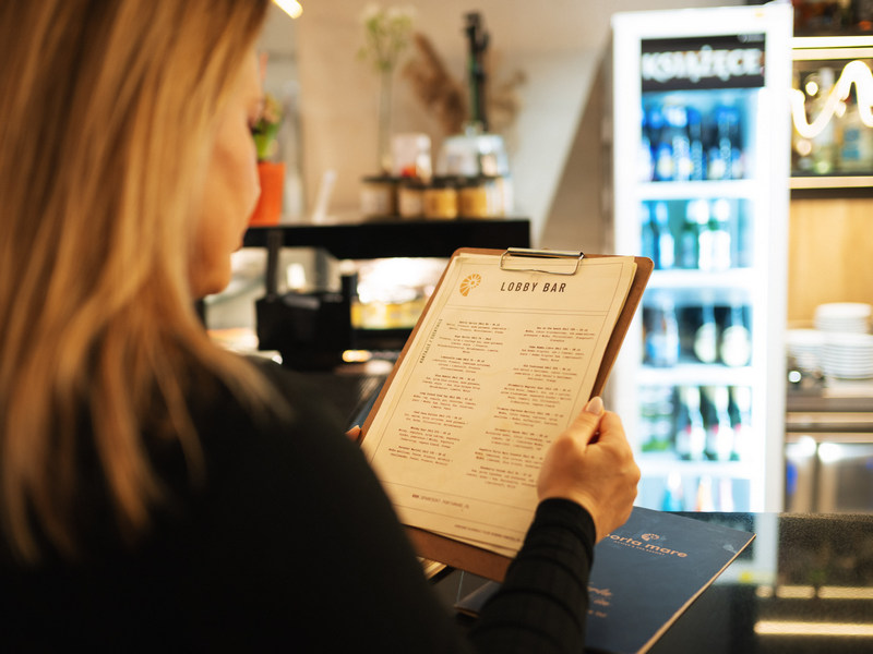 Kobieta czytająca menu lobby baru w hotelu nad morzem