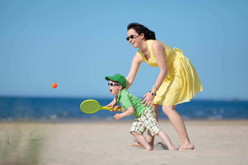Mama z dzieckiem odbijającym piłkę paletką na plaży