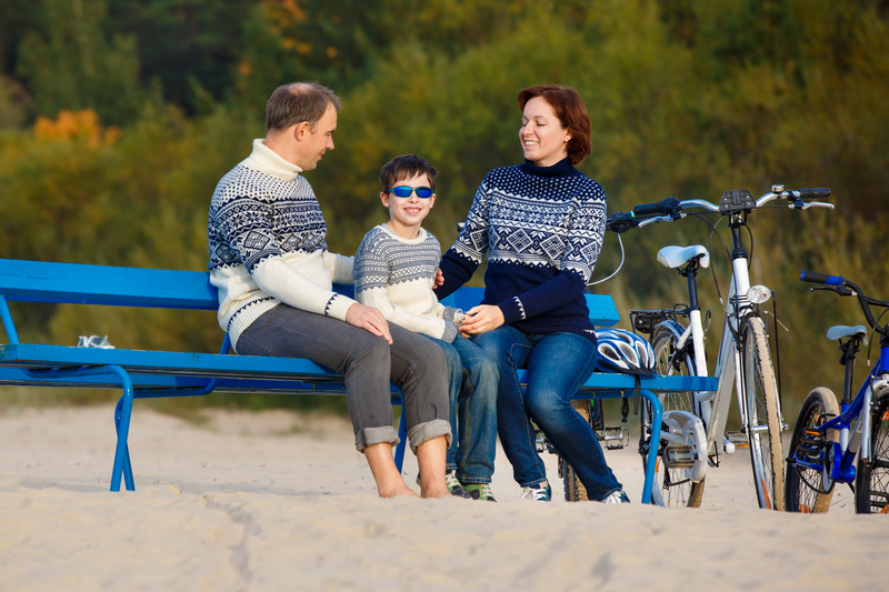 Rodzice z synem na ławce na plaży z rowerami obok