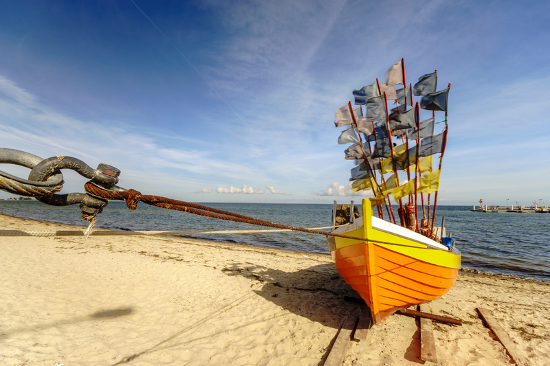 Drewniana, kolorowa łódź rybacka na plaży Morza Bałtyckiego