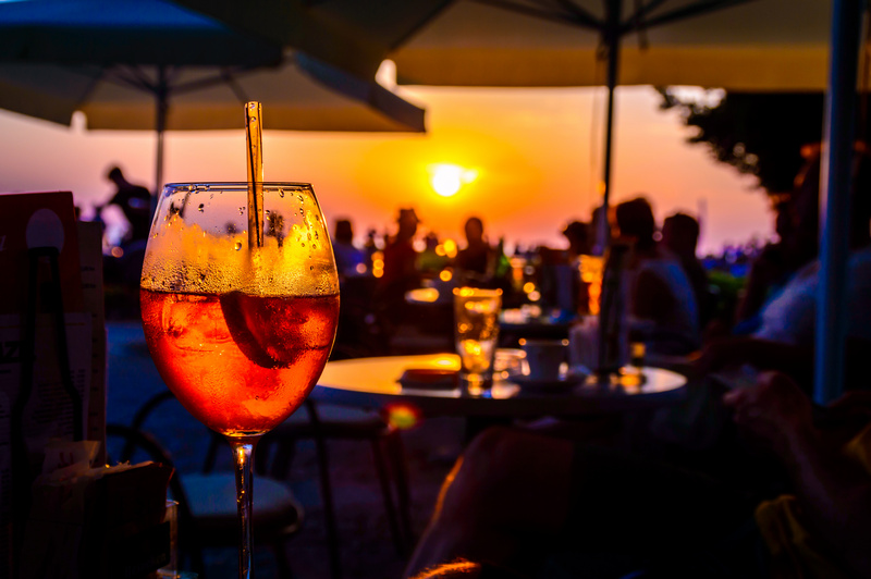 Kieliszek z pomarańczowym drinkiem na tle zachodzącego słońca