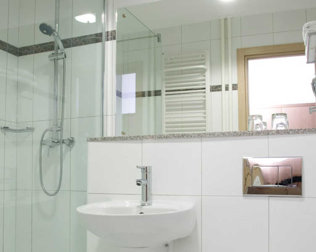 W łazienkach: kabina prysznicowa, suszarka do włosów, ręczniki i kosmetyki